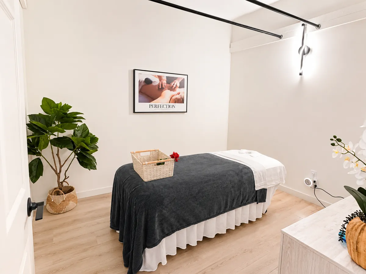Bright treatment room with draped massage table and plants