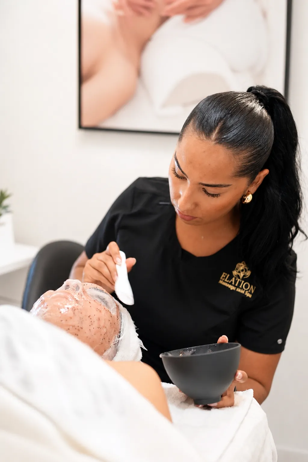 Esthetician applying an exfoliating facial mask