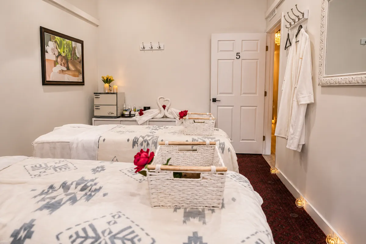 Couples room with side-by-side massage tables and hanging robes
